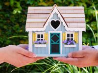 people holding a miniature wooden house