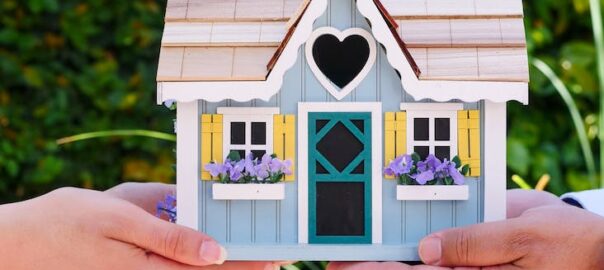 people holding a miniature wooden house