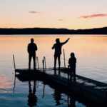 three people on a wooden fishing docks