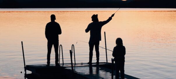 three people on a wooden fishing docks