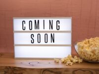 a coming soon sign by a bowl of popcorn