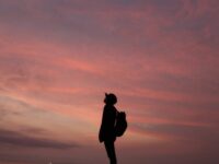 silhouette of man standing on rock during sunset