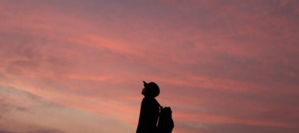 silhouette of man standing on rock during sunset